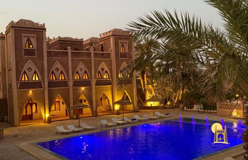 a resort with a swimming pool in front of a building at hotel riad kasbah sbai palace in Mhamid
