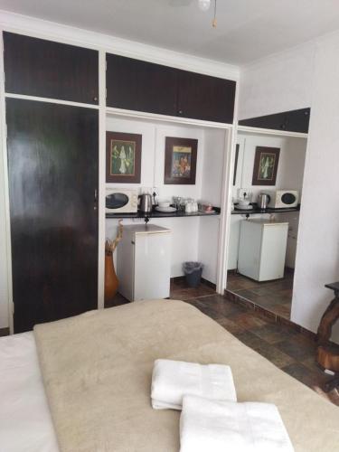 a bedroom with a large bed and a kitchen at Ukarimu Guest House in Klerksdorp