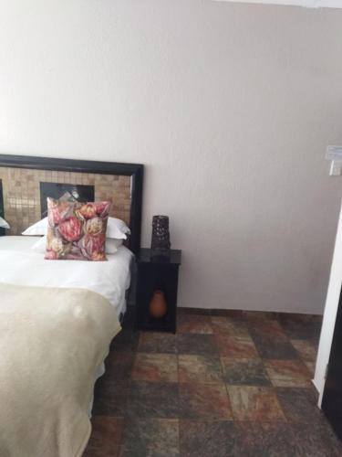 a bedroom with a bed and a tiled floor at Ukarimu Guest House in Klerksdorp