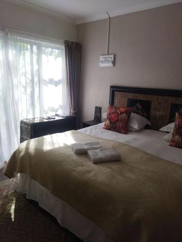 a bedroom with a large bed with two towels on it at Ukarimu Guest House in Klerksdorp