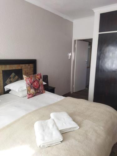 a bedroom with two white towels on a bed at Ukarimu Guest House in Klerksdorp