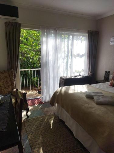 a bedroom with a bed and a large window at Ukarimu Guest House in Klerksdorp