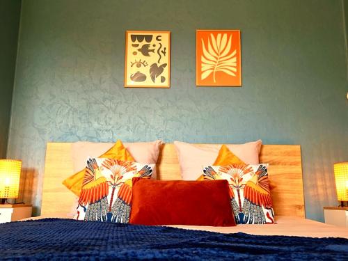 a bedroom with a bed with pillows and pictures on the wall at L'Alcôve de l'Olivier - Studio cosy proche gare in Caen