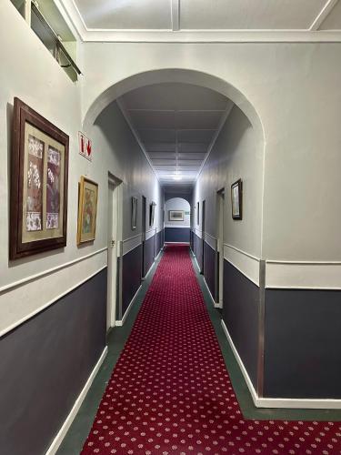 a hallway with a red carpet in a building at The Royal Lodge in Beaufort West