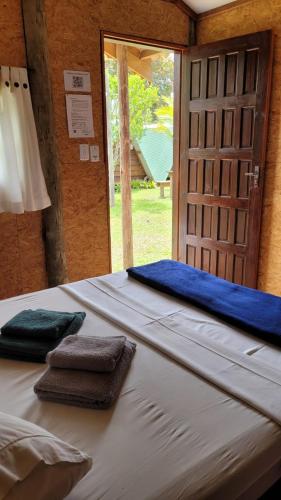 a bed in a room with two towels on it at Piratas Cabanas Camping Bar in Parati-Mirim