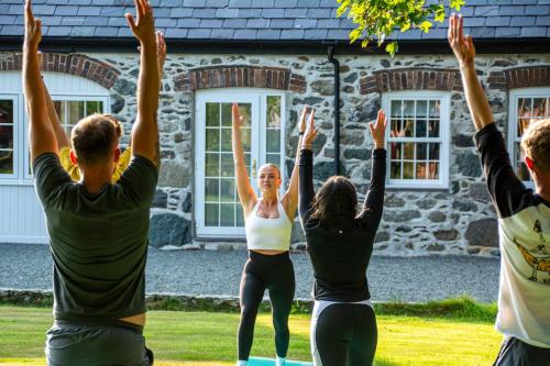 a group of people doing yoga in front of a stone house at The Old Dairy in Holyhead