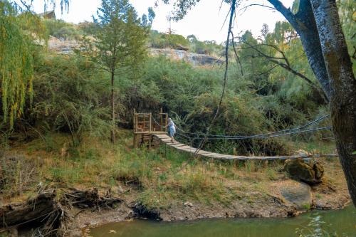 a person crossing a suspension bridge over a river at Camelroc Guest Farm in Fouriesburg