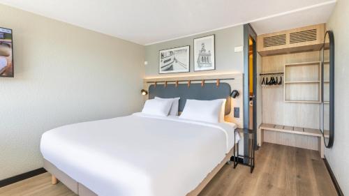 a bedroom with a large white bed with white pillows at Campanile NATURE - Marseille Saint-Antoine in Marseille