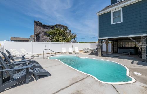 a swimming pool with chairs and a house at Experience Ocean Views at Pinstripe Paradise, 5 BR, Pool, Pets OK! in Avalon Bench