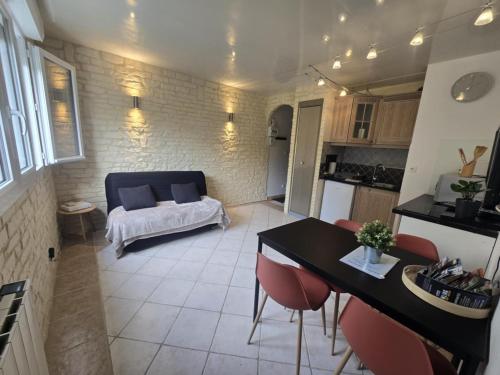 a kitchen and a living room with a table and chairs at Très jolie F2 à 250m de la plage in Courseulles-sur-Mer
