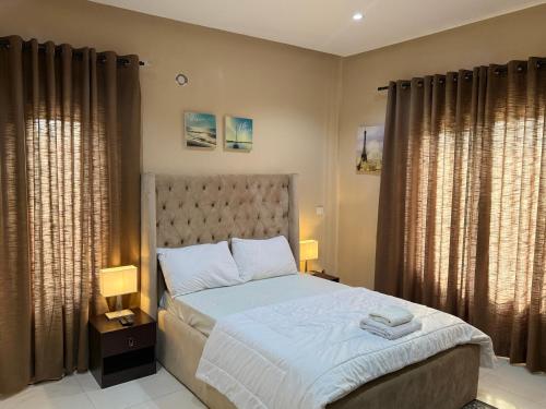 a bedroom with a bed with two lamps and curtains at Luxury 2-bed w 24h light in Kolapo Ishola GRA in Ibadan
