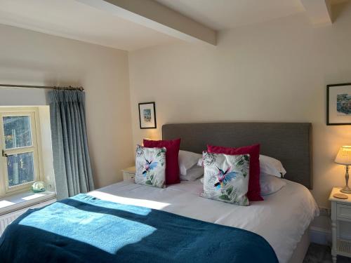 Un dormitorio con una cama grande con almohadas rojas. en Pretty Cotswold Cottage with garden near Bibury, en Quenington