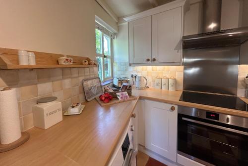 una cocina con armarios blancos y un aparato de acero inoxidable en Pretty Cotswold Cottage with garden near Bibury, en Quenington