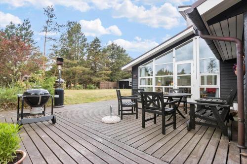 a wooden deck with a grill and chairs on it at TV1486-Jerup-Kuskevej-29 in Jerup