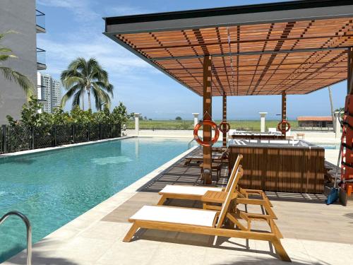 a swimming pool with lounge chairs and a umbrella at Elegancia y Confort en Santa Marta ApartaSuite en Pozos Colorados in Santa Marta