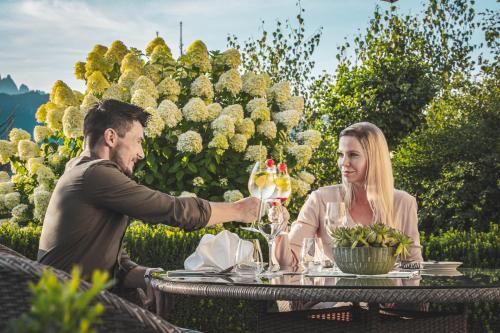 a man and woman sitting at a table with wine glasses at Hotel AlpenSchlössl in Sankt Johann im Pongau