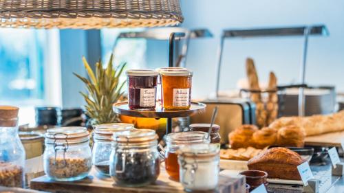 a table with jars of food and bread on it at Campanile NATURE - Dijon Est Saint-Apollinaire in Saint-Apollinaire
