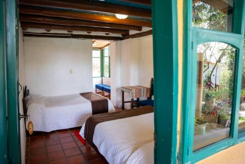 a room with two beds and a window at Hostería Colibri Aeropuerto in Tababela