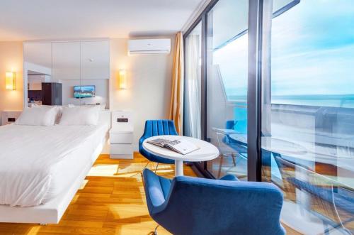 a bedroom with a bed and a table and chairs at PANORAMA Luxury Hotel Batumi in Batumi