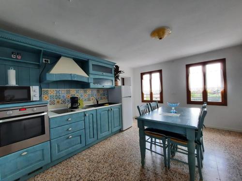 a kitchen with blue cabinets and a table with chairs at The garden holiday apartment in Borso del Grappa
