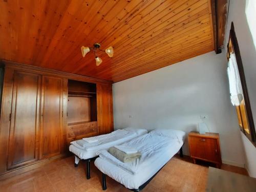two beds in a room with a wooden ceiling at The garden holiday apartment in Borso del Grappa