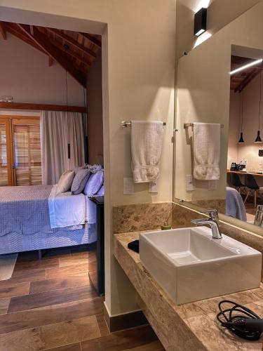 a bathroom with a sink and a bed in a room at Terrace Chalés in Monte Verde