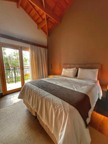 a bedroom with a large bed and a large window at Terrace Chalés in Monte Verde