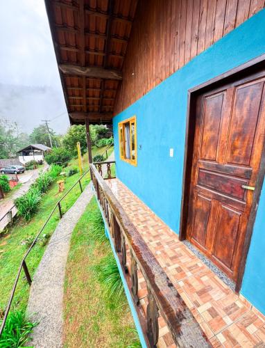 a blue building with a wooden door on the side at Chalés Cerejeira in Visconde De Maua