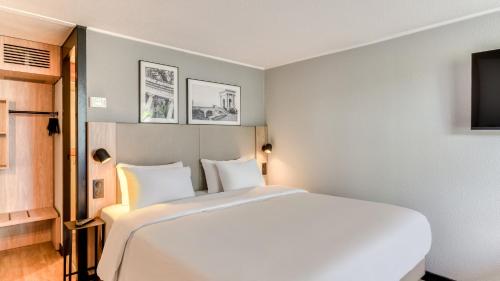 a bedroom with a large white bed and a tv at Campanile NATURE - Dijon Est Saint-Apollinaire in Saint-Apollinaire