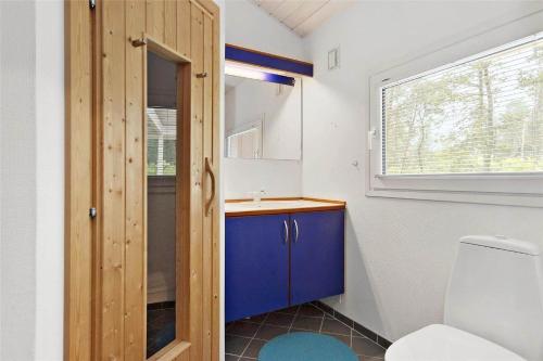 a bathroom with a toilet and a blue cabinet at TV1285-Bindslev-Tannisgardvej-16 in Bindslev