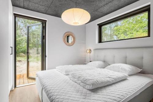 a white bedroom with a large bed and a window at TV1572-Albaek-Lovevej-18 in Ålbæk