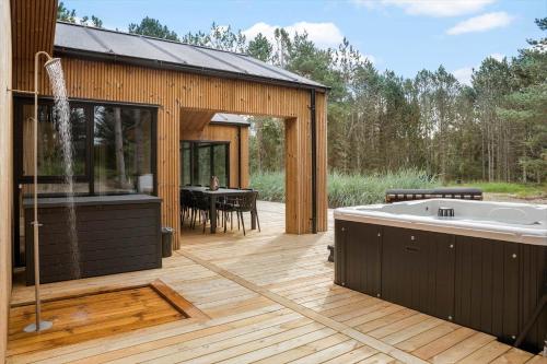 a large deck with a tub and a dining area at TV1572-Albaek-Lovevej-18 in Ålbæk