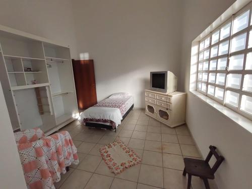 a room with a bed and a tv and a chair at Casa Amarela in Goiás