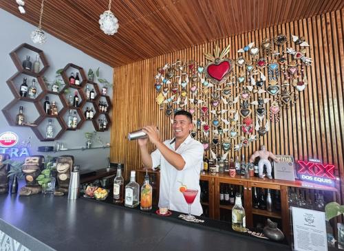 a man standing behind a bar with a drink at Casa Chukum - Hotel Boutique in Bacalar