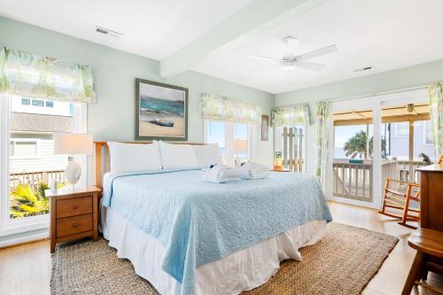 a bedroom with a bed with a blue bedspread and windows at 1709 E Ashley Bacon in the sun in Folly Beach