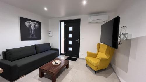 Una sala de estar con un sofá negro y una silla amarilla. en Logement neuf au centre de Martigues avec parking, en Martigues