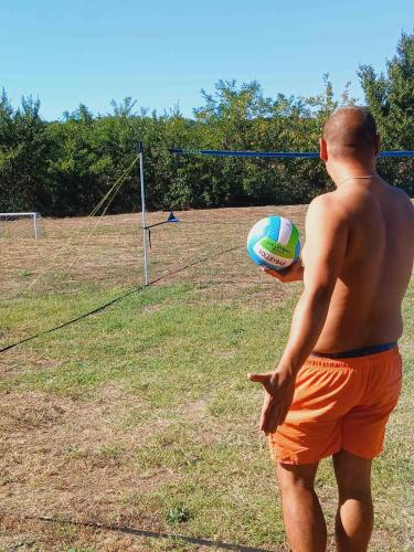 a man in orange shorts holding a volley ball at Sunny Side Fruska Gora - veliko imanje sa kucom za odmor in Velika Remeta
