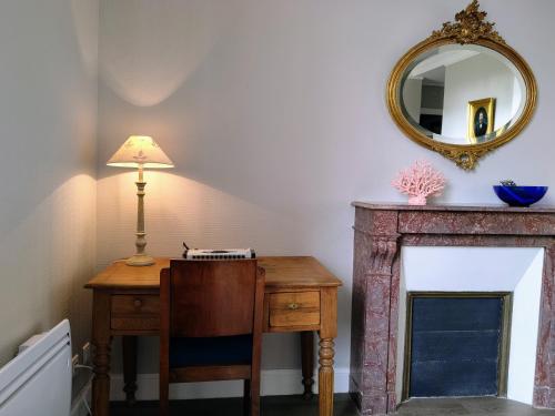 a desk with a lamp and a mirror over a fireplace at Emplacement exceptionnel Appartement très lumineux au cœur de Cabourg in Cabourg