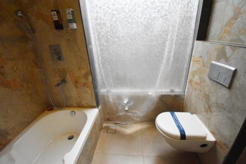 a bathroom with a tub and a toilet and a sink at Aurobay Resorts Pondicherry in Auroville