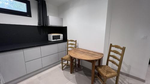 Una pequeña cocina con una mesa de madera y dos sillas. en Martigues centre logement neuf avec parking, en Martigues