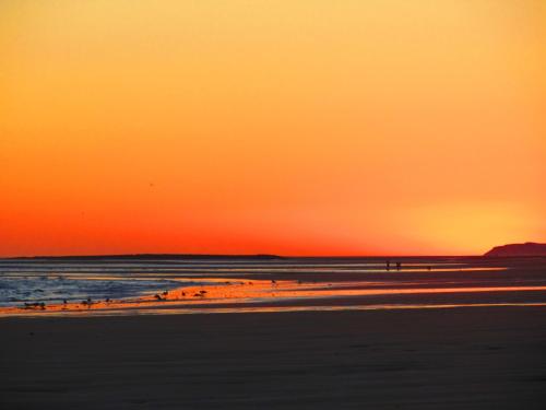 a sunset at the beach with people on the sand at Playa Encanto Scenic Gem Ocean Front Home in Playa Encanto