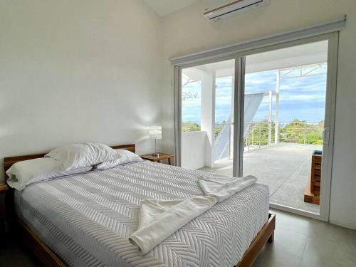 Un dormitorio con una cama y una puerta corrediza de vidrio. en Casa Blanca Manuel Antonio A3, en Manuel Antonio
