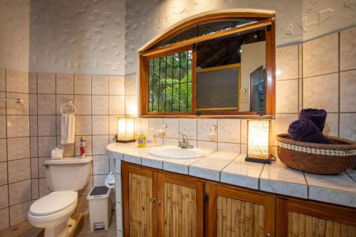 ein Badezimmer mit Toilette und Waschbecken und einem Fenster in der Unterkunft Casa Pura Vida Manuel Antonio in Manuel Antonio