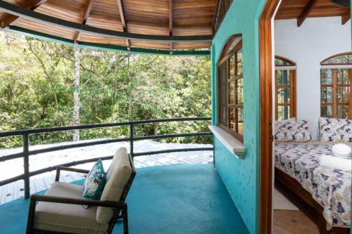 Zimmer mit einem Bett und einem Stuhl auf einem Balkon in der Unterkunft Casa Pura Vida Manuel Antonio in Manuel Antonio