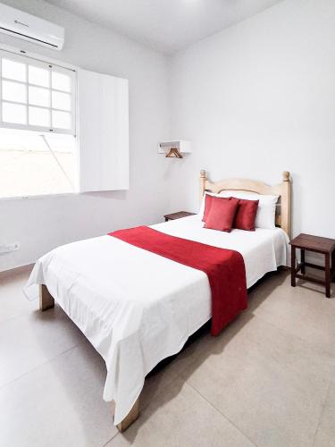 a white bedroom with a large bed with red pillows at Flats Jardim de Ramos em Paraty, RJ in Paraty