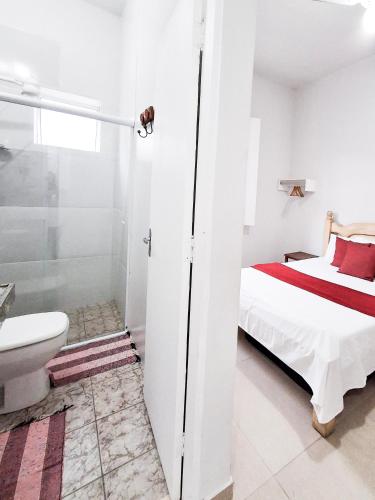 a bedroom with a bed and a shower and a toilet at Flats Jardim de Ramos em Paraty, RJ in Paraty
