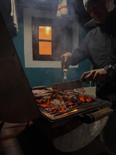 a man is cooking food on a grill at Chalés Cerejeira in Visconde De Maua