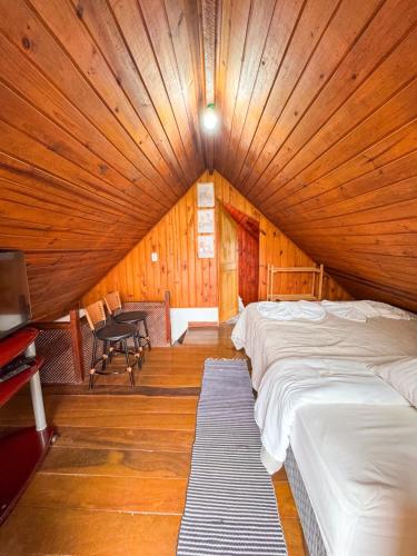 a room with two beds and a table in it at Chalés Cerejeira in Visconde De Maua