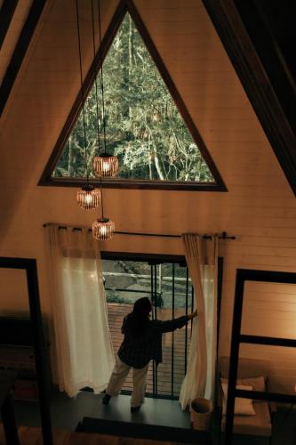 a person standing in a room looking out of a window at Cabana na Serra Rs in São Francisco de Paula