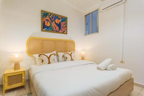 a white bedroom with two beds and a window at Galleria - Heritage 1-BR Apartment in Old Souk Batroun in Batroûn